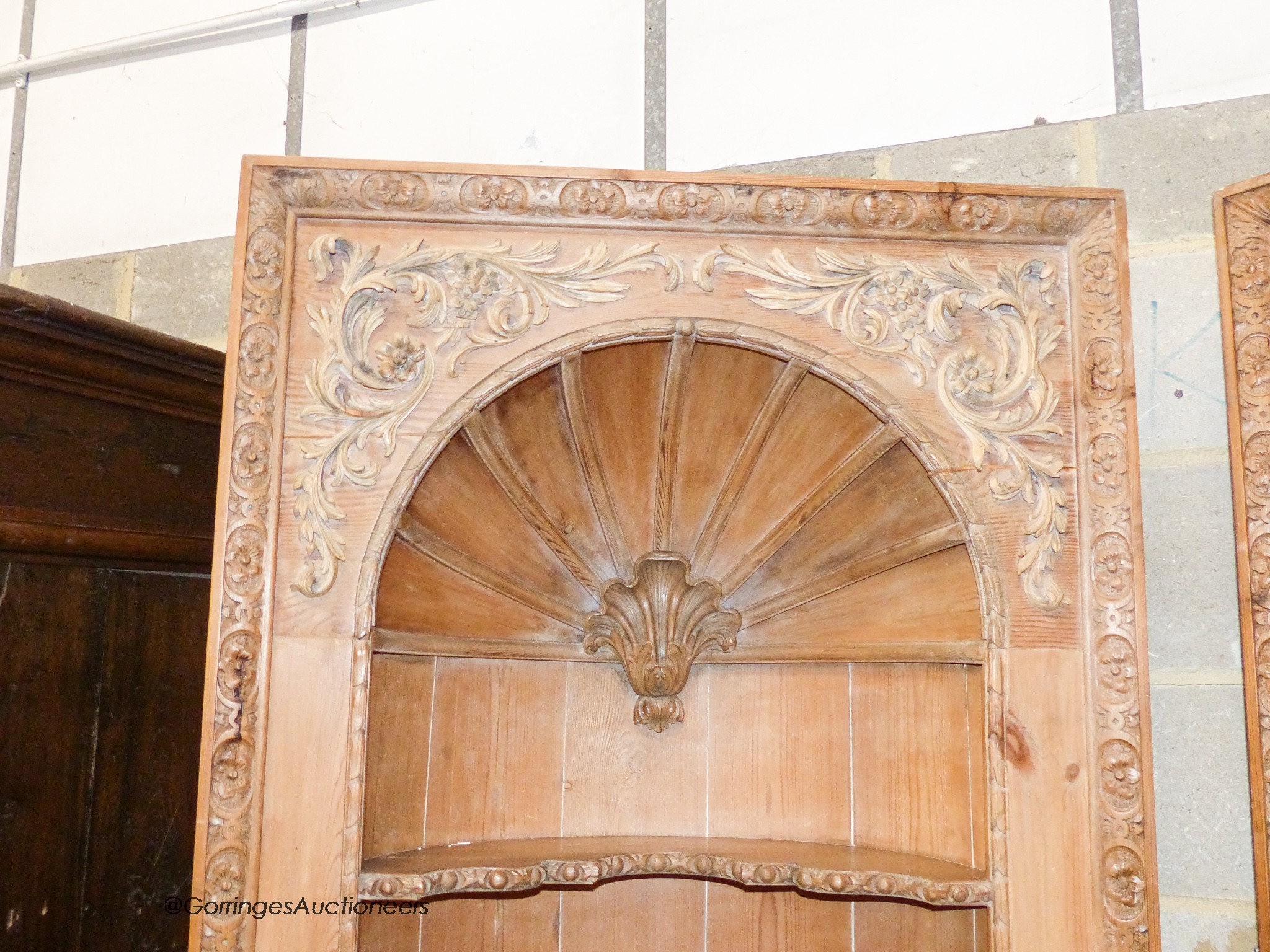 A pair of George III style carved stripped pine niche barrel back open corner cupboards, width 90cm, depth 40cm, height 208cm